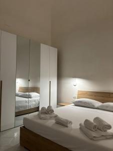 a white bedroom with two beds and a mirror at SALE E LUCE in Trapani