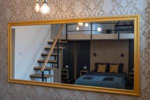 a mirror reflecting a bedroom with a bed and a staircase at Sunflower Apartment in Belgrade