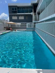 uma piscina com água azul em frente a um edifício em Posada Centric Studio Isla Verde em San Juan