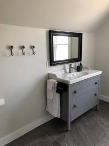 a white bathroom with a sink and a mirror at Hill Street Hangout in Picton