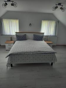 a bed in a bedroom with two windows at Casa de vacanta in Geoagiu Băi