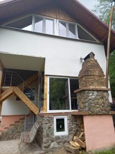 a house with a stone fireplace in front of it at Casa de vacanta in Geoagiu Băi