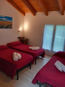a room with four red beds in a room at La collinetta B&B in Crespellano
