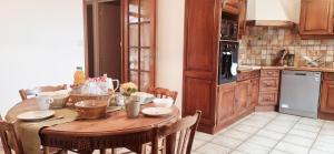 a kitchen with a wooden table with chairs and a tableablish at La maison d’Emilie in Margès +17 photos