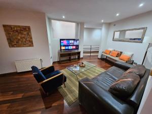 a living room with a leather couch and a television at Lastarria Hotel & Aparts in Santiago