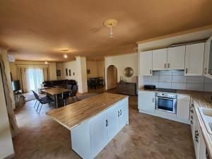 a kitchen with white cabinets and a dining room with a table at Morfi Serenity Retreat in Parga