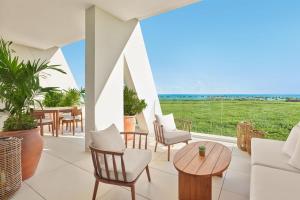 a patio with chairs and tables and a view of the ocean at The Riviera Maya EDITION at Kanai in Playa del Carmen