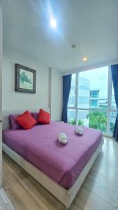 a bedroom with a large purple bed with red pillows at The Base Condominium Behind Central Festival Phuket By T in Ban Rangeng +8 photos