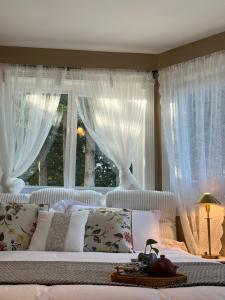 Cama blanca con cortinas blancas y ventana en Gorgeous Private Estate With Ocean and Mountain View en Nanoose Bay