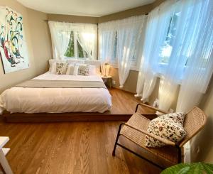 1 dormitorio con 1 cama, 2 ventanas y 1 silla en Gorgeous Private Estate With Ocean and Mountain View, en Nanoose Bay