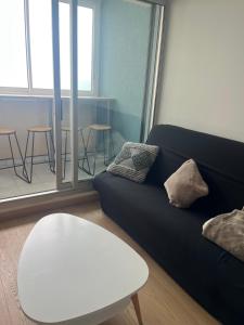 a living room with a black couch and a table at Appartement vue mer in Sète