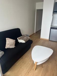 a living room with a black couch and a white table at Appartement vue mer in Sète