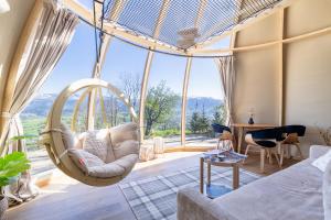 a room with a swinging chair in front of a large window at ZakoGlamp Glamping Pod Gubałówką z Jacuzzi in Ząb