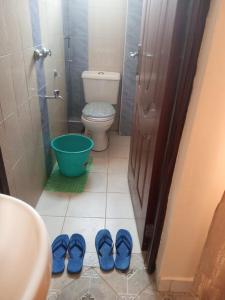 uma casa de banho com WC e um par de sapatos azuis em Gloria House em Nairobi