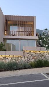 a house with a stone retaining wall and a stone fence at Green Gem Villas Palase 82A in Green Coast in Dhërmi
