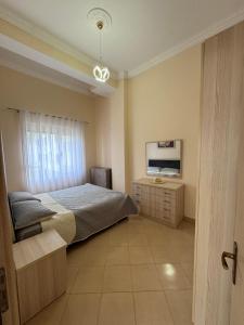 a bedroom with a bed and a dresser and a television at Durres Lovely Apartment with Balcony in Durrës