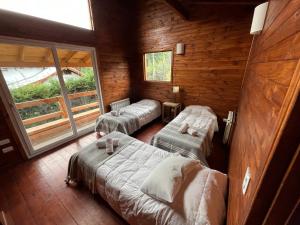 a room with three beds in a log cabin at Hogar de Montaña in Villa La Angostura