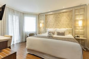 Un dormitorio con una gran cama blanca con un osito de peluche. en Hotel Jardins da Colina, en Nova Petrópolis