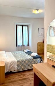 una camera con letto, scrivania e specchio di Albergo Varone a Riva del Garda