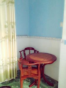 ein Holztisch und zwei Stühle neben einem Tisch und einem Vorhang in der Unterkunft Phú Thông in Chau Doc