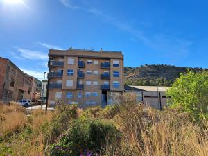a tall apartment building with a hill in the background at La Bonita Ador Apartamento in Ador