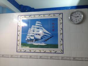 a clock and a picture of a ship on a wall at Phú Thông in Chau Doc