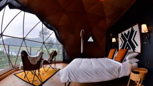a bedroom with a bed in a room with a large window at Lobo Glamp corral de piedra in Amanalco de Becerra