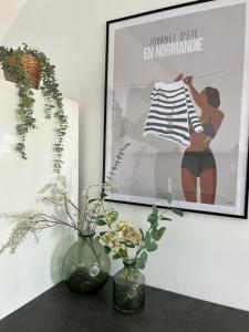 two vases on a table with a picture and flowers at Cosy apartment with large terrace near the beach in Barneville-Carteret