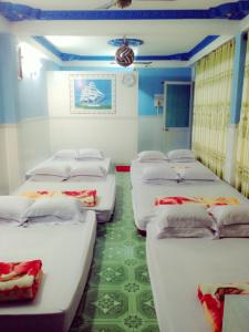 eine Reihe von Betten in einem Zimmer mit grünem Boden in der Unterkunft Phú Thông in Chau Doc