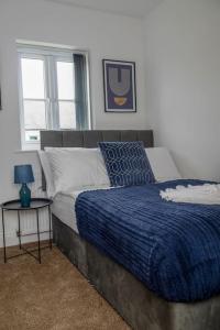a bedroom with a bed with a blue blanket and a table at Short Stays, Free Parking, Contractors, Families - Large Home in Durham