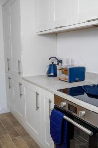a kitchen with white cabinets and a blue kettle on the counter at Short Stays, Free Parking, Contractors, Families - Large Home in Durham +13 photos