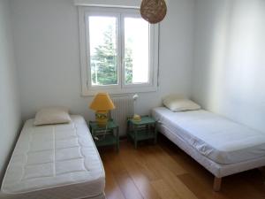ein Zimmer mit zwei Betten und einem Tisch mit einer Lampe in der Unterkunft Appartement dans résidence, plage et centre ville à pied in Saint-Jean-de-Luz