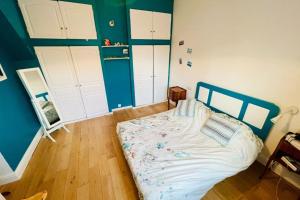 1 dormitorio con 1 cama con paredes azules y armarios blancos en Charming House Ideally Located With Furnished Terrace 3 Bedrooms & Parking en Le Bouscat