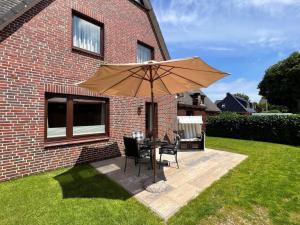 un tavolo e sedie sotto un ombrellone in un cortile di Johannsen-Huis-Appartement-Bent a Tinnum