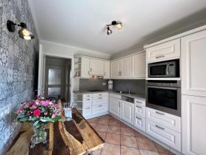 - une cuisine avec des placards blancs et une table fleurie dans l'établissement Johannsen-Huis-Appartement-Bent, à Tinnum