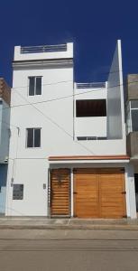 un bâtiment blanc avec deux portes de garage dans une rue dans l'établissement Malabrigo's House - On Puerto Chicama Dpto I, à Puerto Chicama