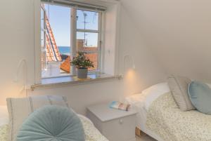 1 dormitorio con cama, ventana y silla en Pension Slægtsgaarden en Allinge