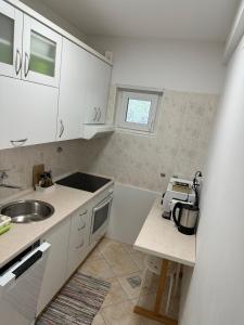 Villa Hosta Apartments في هفار: مطبخ صغير مع دواليب بيضاء ومغسلة