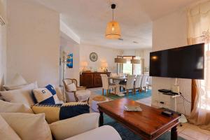 ein Wohnzimmer mit weißen Möbeln und einem Flachbild-TV in der Unterkunft Luxus Villa Cristina - mit Pool und Meerblick by Riviera HomeLife in Roquebrune-sur-Argens