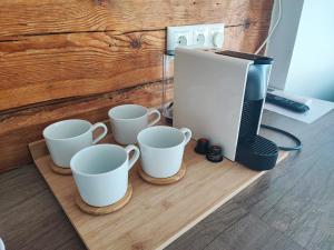 a coffee maker and four coffee cups on a counter at Lainela puhkeküla in Käsmu