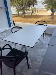two white tables and a black chair in front of a window at Nikoletta Studios in Agios Prokopios
