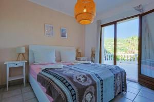 ein Schlafzimmer mit einem Bett und einem großen Fenster in der Unterkunft Luxus Villa Cristina - mit Pool und Meerblick by Riviera HomeLife in Roquebrune-sur-Argens + 17 Fotos