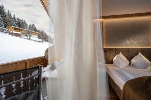 a bedroom with a bed and a window with a view at Almhotel Lenz in Valdaora
