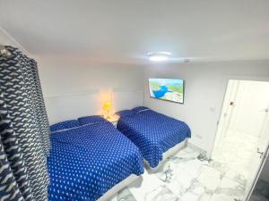 a bedroom with two beds with blue sheets at THE ROYAL BOUTIQUE WESTMINSTER LODGE by LONDON SLEEP 10 in Hayes