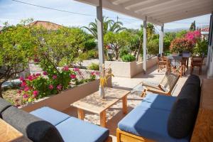 une terrasse avec des canapés bleus, des tables et des fleurs dans l'établissement Villa Primarosa, à Metaxáta