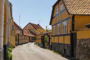 un callejón con casas amarillas y negras en una calle en Pension Slægtsgaarden en Allinge