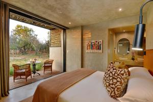 a bedroom with a bed and a patio with a table at Ngala Lodge in Klipdrift
