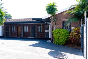 ein Backsteinhaus mit Palmen davor in der Unterkunft Inkanyezi Guest house in Durban