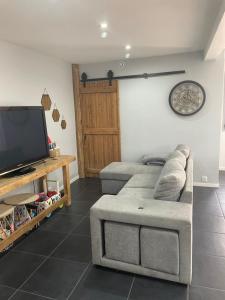 a living room with a couch and a flat screen tv at L'Imprévu est une maison individuelle. in Sennecey-le-Grand