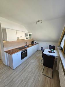 a kitchen with white cabinets and a table with a sink at Haus am Bodden in Fuhlendorf